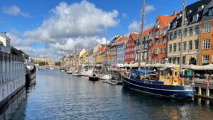 Old wooden boats in Copenhagen, moored in front of brightly painted warehouses.
